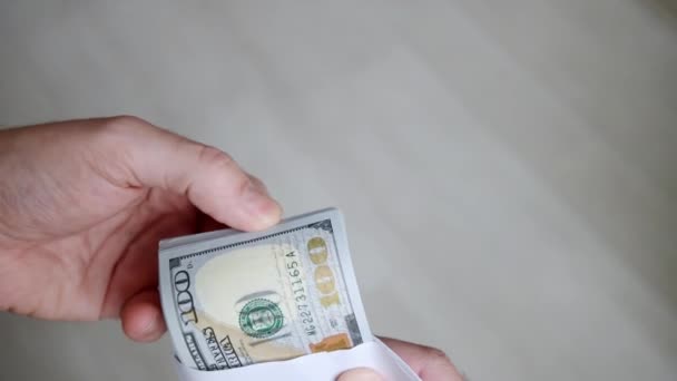 Pria tangan dengan amplop penuh uang seratus dolar. Seorang pria menunjukkan dan menghitung uang kertas baru. Konsep menyimpan uang atau korupsi dan bayangan ekonomi. Gerakan lambat — Stok Video