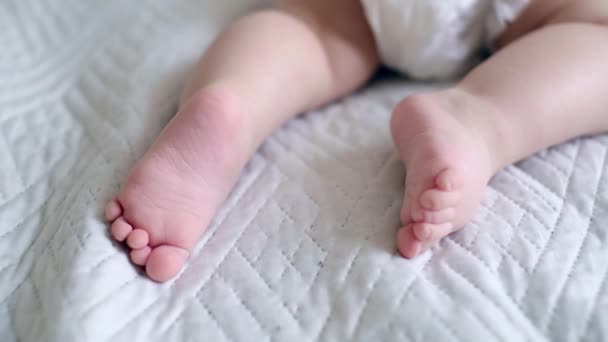 Zbliżenie do poruszających się noworodków stóp i nóg. słodkie małe nogi dziecka na białym prześcieradle — Wideo stockowe