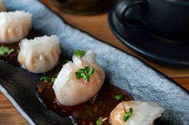 Geleneksel Çin mantısı. Karides ve bambuyla birlikte Çin mantısı. Asya hamur köftelerini siyah tabağa koy. Geleneksel Asya mutfağı, Çin mezesi..