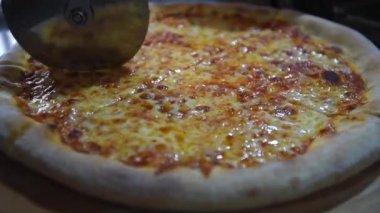 Şef taze malzeme eklemeden önce pizzayı parçalara ayırdı. Yakın plan.