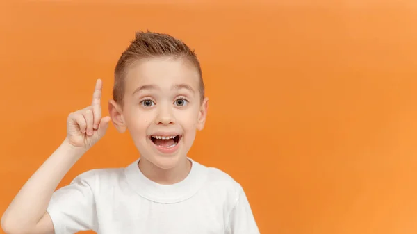 Bambino in età prescolare hanno grande idea. Finger indicando una grande idea isolata su sfondo arancione. Ritratto ravvicinato di un bel ragazzino allegro. Copia spazio per il tuo testo o prodotto — Foto Stock