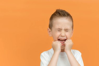 İzole edilmiş arka planda dikilen tişörtlü çocuk öfkeli ve öfkeliydi. Öfkeliydi ve öfkeliydi. Çocuk bağırması. Duygu konsepti. Boşluğu kopyala