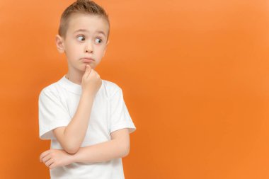 Komik, düşünceli anaokulu çocuğunun portresi elini çenesinin altında tutuyor, bir şey hatırlamaya çalışıyor ya da ilgi çekici bir şey dinliyor. Hayalperest, güzel küçük çocuk. Karar alma kavramı