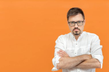 Etkilenmedim. Ciddi bir beyaz adam hayal kırıklığına uğramış ve hayal kırıklığına uğramış hissediyor, kameraya bakıyor, kızgın ve kızgın turuncu arka planda izole edilmiş kollara sahip. Boşluğu kopyala