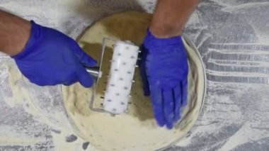 Lastik eldivenli erkek eller pizza hamurunu deliyor. Aşçı hamur pizza tabanı oluşturur.. 