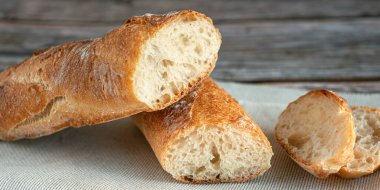 Yarım baget dilimlenmiş. Ekmeği yakından çek. Ahşap zemin üzerinde taze pişmiş ekmek. Lezzetli Fransız ekmeği