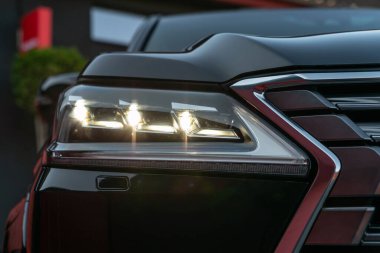 Siyah, lüks, modern bir arabanın ön farları. LED farlarından birinin detaylarını modern araba fişeğiyle kapat.