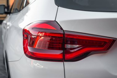 Yeni bir modern beyaz arabanın kırmızı farları. Prestij SUV arabasının arka stop ışığı. Beyaz prim şehir geçişi.