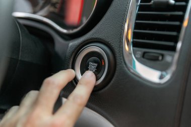 Erkeğin parmağı başlatma düğmesine basıyor, lüks arabadaki motoru durduruyor..