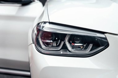 Front headlight of a white luxury modern suv car close up