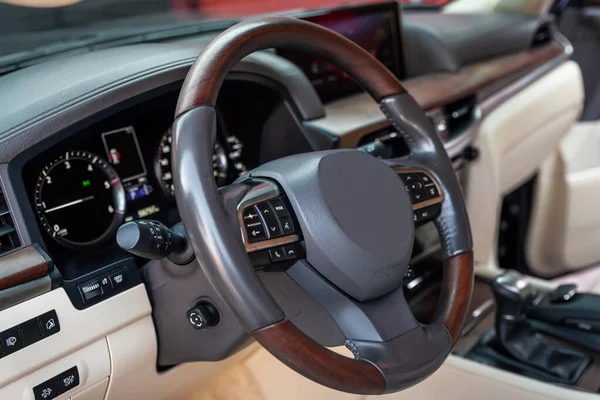 Painel do carro e volante com botões de controle de mídia. cockpit bege com decoração de madeira exclusiva. Interior do veículo de luxo. — Fotografia de Stock