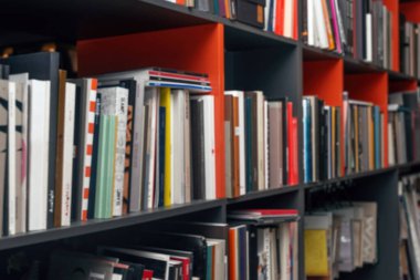 Raflarda çok renkli kitap ve kataloglarla bulanık arkaplan.