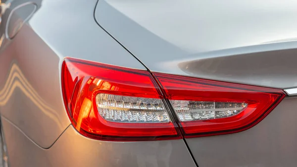 O farol vermelho de um moderno carro metálico sedan. Luz de travagem traseira. Premium LED sedan faróis traseiros. Imagem De Stock