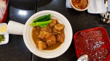 Sıcak kase içinde lahana, kırmızı tepside taze ciğer, dilimlenmiş yeşil biber ve siyah yemek masasında sarımsaklı domuz pirzolası. Baharatlı ya da ekşi soslu erişte..