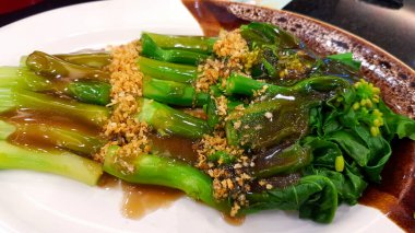 Hong Kong lahanası, istiridye sosu ve Çin restoranında beyaz tabak ya da tabakta kurutulmuş sarımsak. Lezzetli Asya yemekleri.