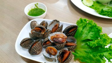 Taze deniz tarağı ya da yeşil lahana ile beyaz tabak ya da tabakta ve Tayland usulü baharatlı ekşi sos ahşap masada deniz ürünleri restoranında fotokopi alanı ile birlikte. Asya yemeği ve Lezzetli yemek.