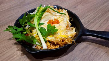 Tayland usulü kızarmış şehriye, karidesli ve sebzeli ahşap arka planda sıcak tavada veya restoranda bir masada. Asyalılar buna Tayland 'da Pad Thai ve Ünlü diyorlar. Lezzetli yemek.