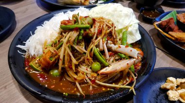 Tayland baharatlı papaya salatası, tuzlu yengeç ve mayalanmış balıkla birlikte siyah tabak veya tabakta pirinç eriştesi. Tayland 'da ünlü yemekler ve lezzetli yemekler..