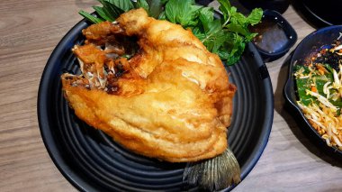 Balık soslu levrek ve siyah tabakta taze fesleğen yaprağı. Asya yemeği ve Lezzetli yemek