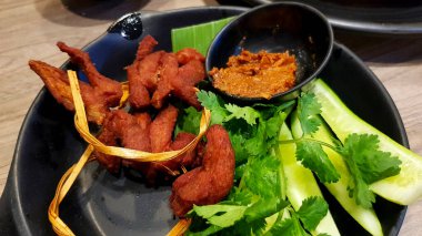 Tayland usulü kızarmış domuz eti, kıyılmış balık, taze salatalık ve Isaan restoranındaki siyah tabak ya da tabakta. Asya yemeği ve Lezzetli yemek.