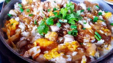 Taze istiridye omletini yumurtalı, yapışkan aromalı, biraz malzemeli ve deniz ürünleri restoranındaki kapkara kapta pişmiş kişniş soslu. Asya yemekleri ve lezzetli yemekler..