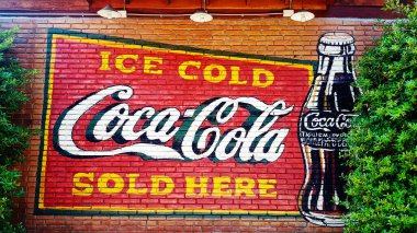 Bangkok, Tayland-5 Eylül 2020: Kahverengi tuğla duvarda lambayla boyanmış renkli Coca-Cola ve dekore edilmiş dükkanlar için yeşil ağaç. Köpüklü su markası ve sanat tasarımı meşhurdur..