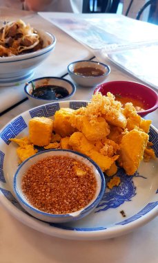 Kızarmış çıtır tofu, beyaz tabakta tatlı fındık sosuyla ya da Çin restoranında tabak ile yenir. Asya yemeği ve atıştırmalığı.