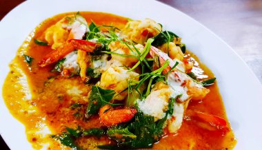 Kırmızı biber dilimlenmiş kırmızı körili karides, kaffir limon yaprağı, fesleğen ve bitkisel karışımı beyaz tabak ya da restoranda. Tayland Baharatlı Yemekler