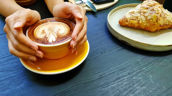Vrouwenhand Met Gele Kop Art Latte Koffie Met Amandelroom Croissant — Stockfoto