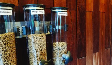 Kahverengi ahşap duvarda asılı üç plastik kahve çekirdeği ya da tohum kavanozu sağ tarafında fotokopi alanı olan bir kafe dükkanında..