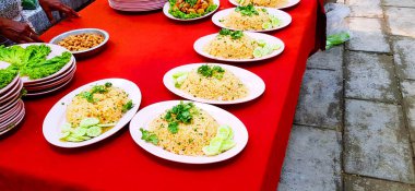 Pembe tabak ya da Tayland pilavı taze sebze, salatalık ve kişniş soslu kırmızı masa. Hazır yemek, müşteriye servis, yemeğe hazır ve ünlü Asya yemekleri konsepti.