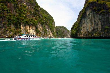 Krabi, Tayland-5 Aralık 2020: Birçok sürat teknesi denizde ve turist, gezgin ya da insanları sahile, Andaman okyanusunu büyük kaya ya da dağ ve mavi gökyüzü arka planıyla gezmeye götürüyor. Yer İmi ve Manzara 