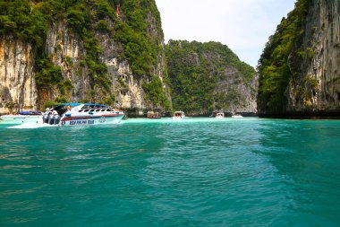 Krabi, Tayland-5 Aralık 2020: Birçok sürat teknesi denizde ve turist, gezgin ya da insanları sahile, Andaman okyanusunu büyük kaya ya da dağ ve mavi gökyüzü arka planıyla gezmeye götürüyor. Yer İmi ve Manzara