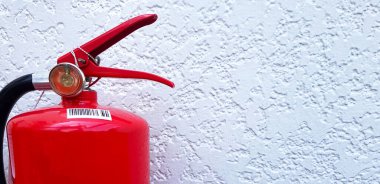 Beyaz beton duvarda kırmızı yangın söndürücü ve sağ tarafında kopya alanı var. Bir nesneyi kapat, ateşi bastırmak için koruyucu araç.