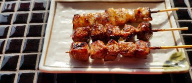 Close up Japanese wagyu beef grilled in white dish or plate on tile table at street food market. Meat barbecue and Famous food in Japan