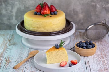 Tahta arka planda yabanmersini soslu lezzetli Tayvan Castella keki..