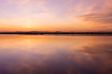 Albufera Gölü, Valencia, İspanya 'da güzel bir turuncu ışık ve dağlık bir arka plan ile gün batımı manzarası.