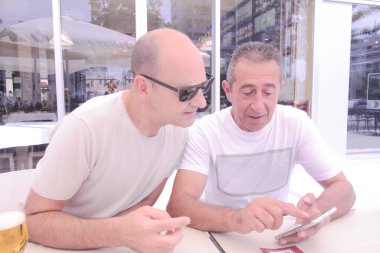 Bir adam başka bir adama cep telefonundaki e-ticaret analizlerine nasıl bakacağını anlatıyor.