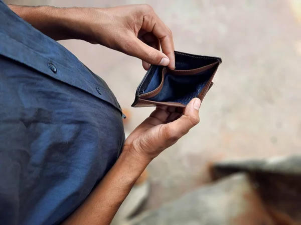 Young man holding empty wallet in hands top view with selective focus