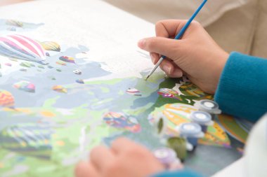 11, sayı tablolarından sıcak hava balonu resmi. Bronz tenli bir genç tarafından resmedilmek. Mavi kazak ve boya fırçası renkleri cilde çarpar