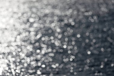 7 - Ekstra büyük beyaz yuvarlak bokeh, güneşe bakarak oluşmuş açık hava rezervuar gölündeki su dalgalanmalarına çarpıyor. Soyut düz arkaplan.