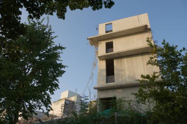 Yıkıma uğrayan büyük beton binayı harap etti. Arka planda endüstriyel beton binalar olan geniş açı. Sabah güneşi, yumuşak gökyüzü