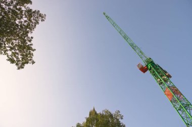 Sabahın erken saatlerinde ağaç tepeleri yapraklarının arkasında yumuşak bir arka plan ve büyük bir kule vincinin önde gelen yelkeni. Bolca kopyalama alanı olan özet.
