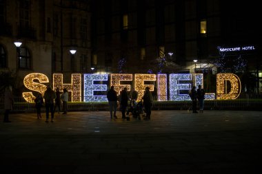 Sheffield, Birleşik Krallık, 27 Kasım 2020 'de Sheffield' e yaklaş ve yılbaşı ışıklarıyla aydınlat. Bir grup insan önde duruyor..
