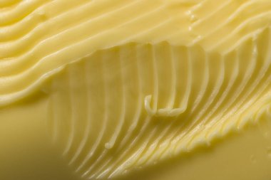 Karmaşık oyukların ve margarin girdaplarının makro arkaplanı süper yakın plan. Yüzeyi tırtıklı mutfak bıçağıyla süpürülmüş..