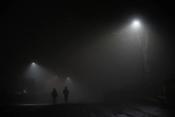 Zwei Geheimnisvolle Männer Mit Kapuzen Laufen Eine Dunkle Nebelige Straße Stockfoto