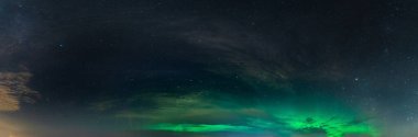 Güzel, yumuşak Aurora Borealis 'in panoramik gerçek fotoğrafı. Kara gece gökyüzünde bulutlu parlak yeşil ışıklar. Kuzey yarımkürede bir sürü gerçek yıldız görünüyor.