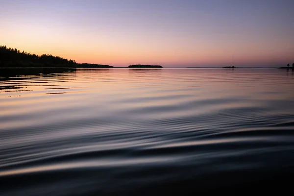 İsveç 'in kuzeyinde yaz gecelerinde gece yarısı deniz güneşi. Su yüzeyi gibi bir ayna. Güneş 'in renklendirdiği pembe bir gökyüzü. Ufkun arkasına saklanmıştı. Umea, Baltık Denizi, İsveç