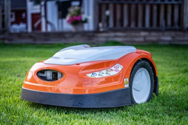Otomatik çim biçme robotu çimlerin üzerinde hareket ediyor. Bulanık arkaplan ile yan görünümü kapat