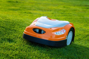 Otomatik çim robotu çim biçme makinesi çim yamacında hareket ediyor. Yan görünümü kapat